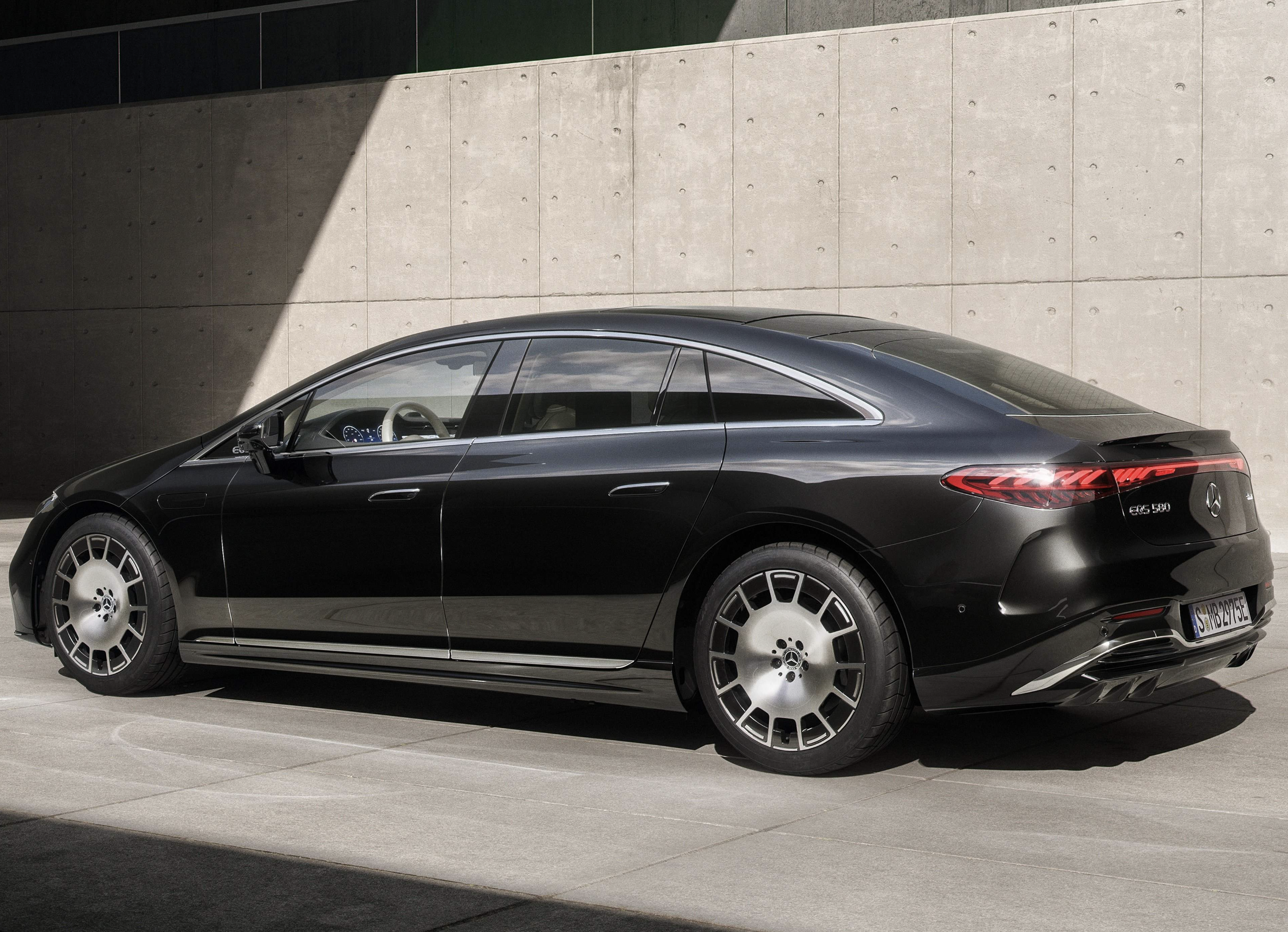Electric luxury sedan cruising on an empty highway at dawn